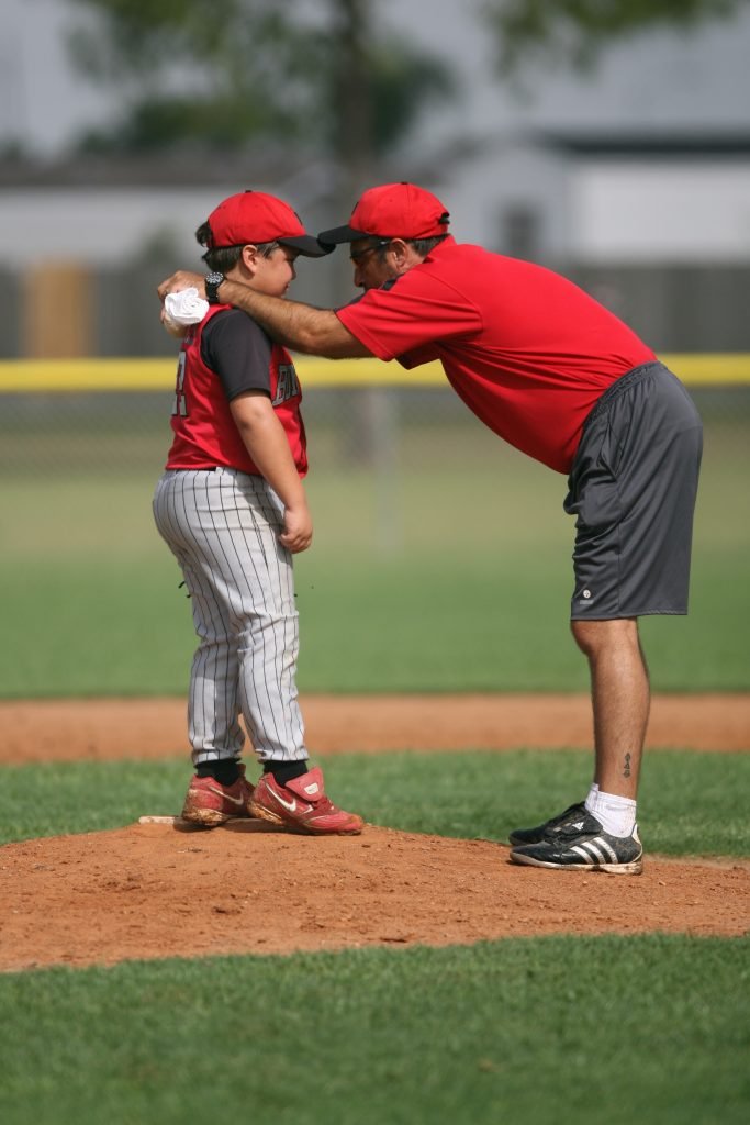 This picture show a coach telling a little child about sportsmanship. This is what baseball in younger years should be about! 