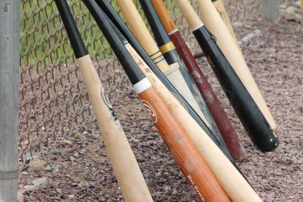 A lot of wood bats standing at a fence. Maybe these are the best baseball bats 2020. 